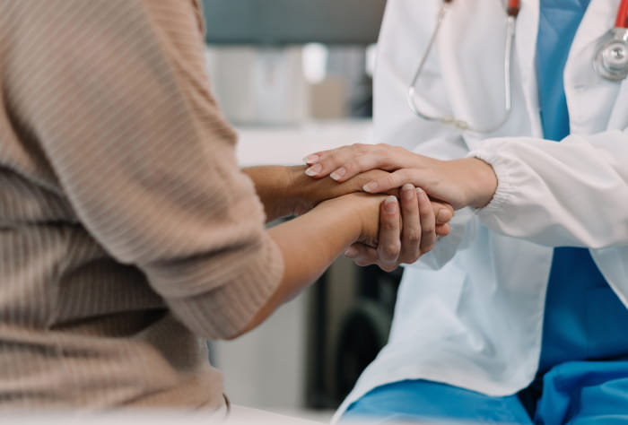 Healthcare professional holding the hands of a patient
